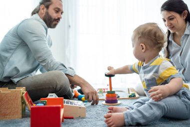 Beyaz, mutlu bir ebeveyn, bebek bebekle oturma odasında oynuyor. Çekici bir çift anne ve baba evde küçük bir çocukla vakit geçiriyor. Ev kavramında etkinlik ilişkisi.