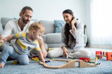 Beyaz, mutlu bir ebeveyn, bebek bebekle oturma odasında oynuyor. Çekici bir çift anne ve baba evde küçük bir çocukla vakit geçiriyor. Ev kavramında etkinlik ilişkisi.