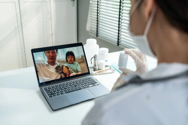 Asian veterinarian girl talk to pet owner on online virtual video call. Professional vet doctor woman use laptop computer to give treatment plan consult for little cat animal while sit in pet hospital