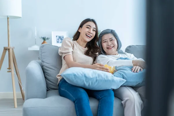 Asyalı yetişkin kadın ve kızı kanepede oturup komik film izler. Yaşlı ve sevecen bir anne evde güzel bir kızla vakit geçirir TV 'de komedi şovu yapar ve birlikte atıştırmalık yerler..