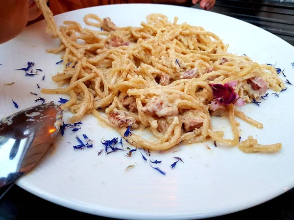 Tahta kasede domates soslu kızarmış domuz eti. Çatal ve baharatlı beyaz tabakta.