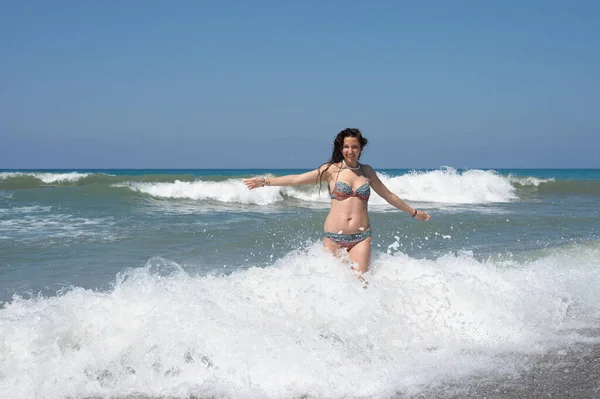 Νεαρή γυναίκα με λευκό πουκάμισο κάνει μπάνιο στα κύματα στον αφρό της θάλασσας σε ένα εξωτικό τροπικό νησί — Φωτογραφία Αρχείου