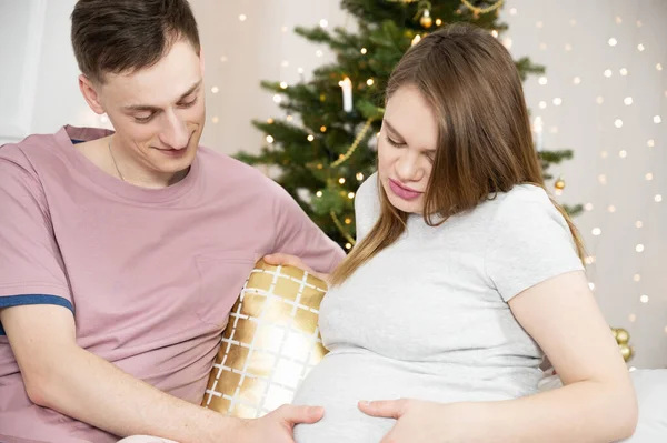 Sorridente coppia incinta in soggiorno. Gravidanza, vacanze invernali e concetto di persone — Foto Stock