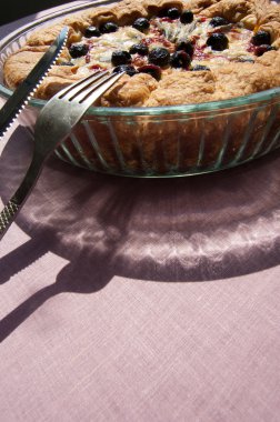 masada, bıçak, yanında bir bardak çanak içine çatal pasta. Masanın üzerinde güneş yansıma.