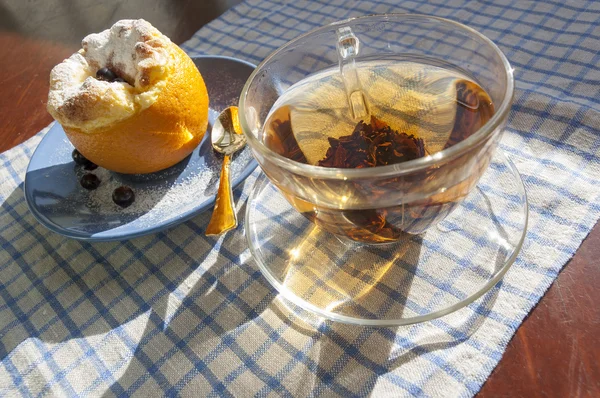 Апельсиновый десерт и стакан чая с золотой чайной ложкой — стоковое фото
