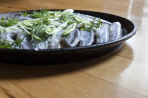 Verse vis bestrooid uien op een oude koekenpan — Stockfoto
