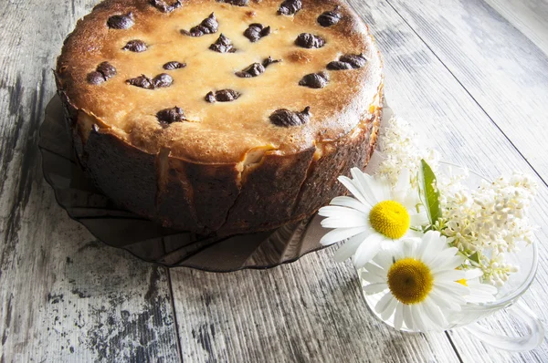 Cheesecake on an old table with a bouquet of camomile. — Stock Photo, Image