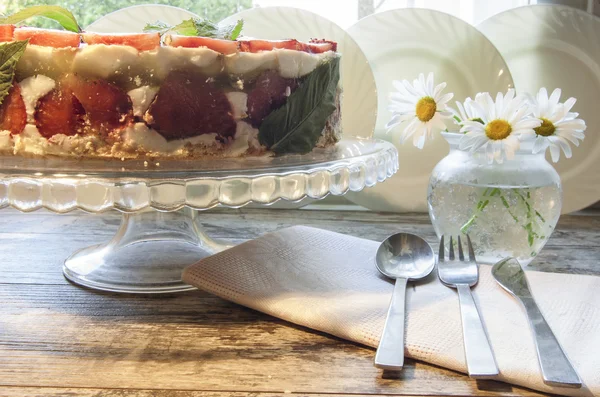Strawberry cake on a glass base with a bouquet of daisies — Stock Photo, Image