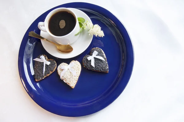 Три свадебных печенья с чашкой кофе на голубой тарелке — стоковое фото