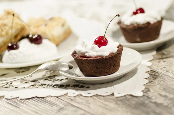 Шоколадний десерт, прикрашений вершками та вишнею — стокове фото