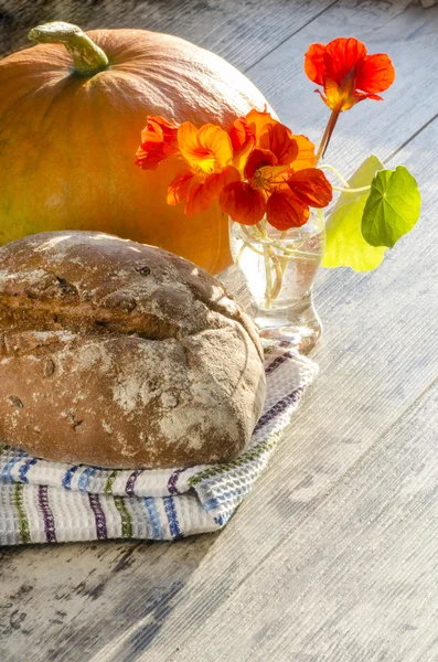 Pane, fiori e zucca sul vecchio tavolo di legno — Foto Stock