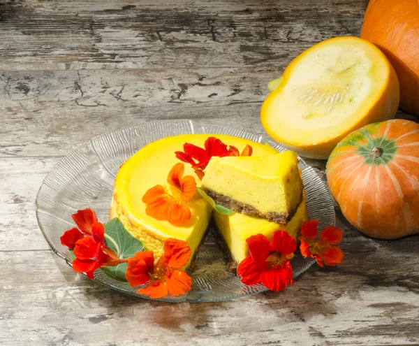 Pumpkin cheesecake decorated with fresh flowers on glas plate