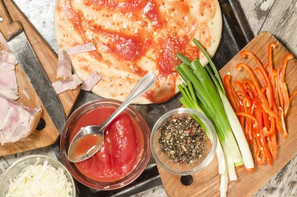 Домашняя пицца на подносе и ингредиенты для приготовления пищи — стоковое фото