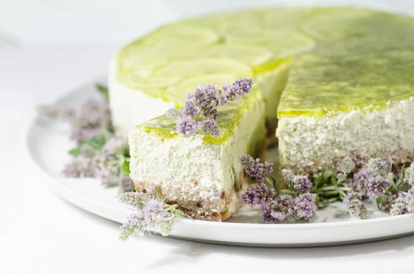 Limetten-Käsekuchen mit Minzblüten verziert, verschwommener Hintergrund — Stockfoto