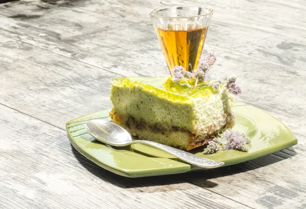 Tranche de gâteau au fromage au citron vert décoré de fleurs de menthe et verre de cognac — Photo