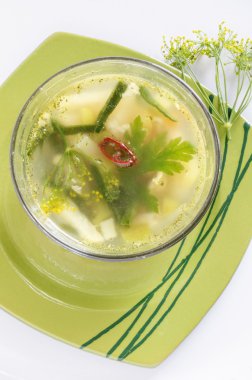 Yeşil plaka üzerinde bir cam kase sebze çorbası