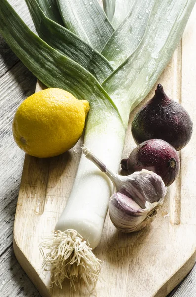 Fresh onion, garlic and lemon on a wooden cutting board. — Stock Photo, Image