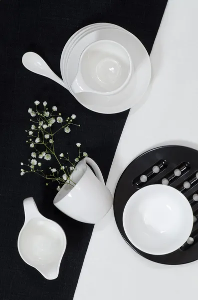 Weißes Porzellan auf schwarzen und weißen Leinentischdecken. — Stockfoto