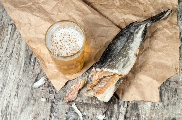 Dry fish with beer on wrapping paper — Stock Photo, Image