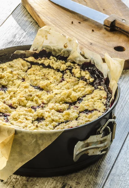 Streuselkuchen mit schwarzen Johannisbeeren auf Backpapier — Stockfoto