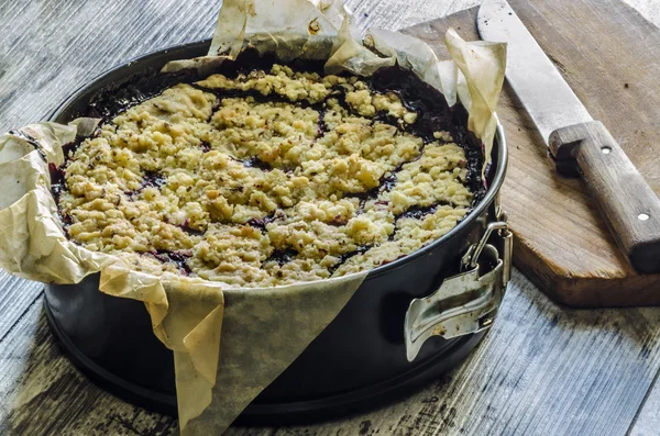 Crumble pie met zwarte krenten op bakken papier — Stockfoto