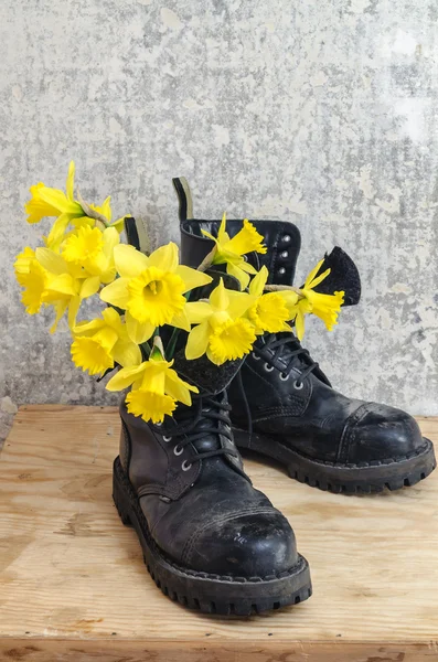 Negro zapatos fangosos militares con narciso amarillo — Foto de Stock