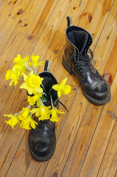 Negro zapatos fangosos militares con narciso amarillo — Foto de Stock
