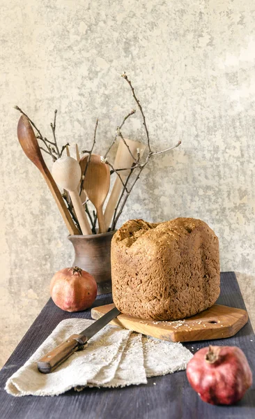 Homemade bread on cutting board with two pomegranates — Stock Photo, Image