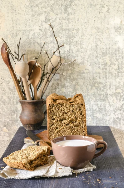 Домашний хлеб на разделочной доске с чашкой молока — стоковое фото