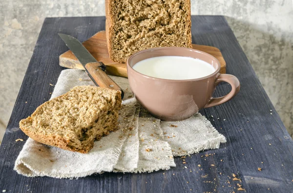 Pane fatto in casa sul tagliere con tazza di latte — Foto Stock