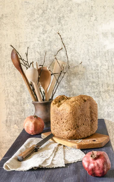 Homemade bread on cutting board with two pomegranates — Stock Photo, Image