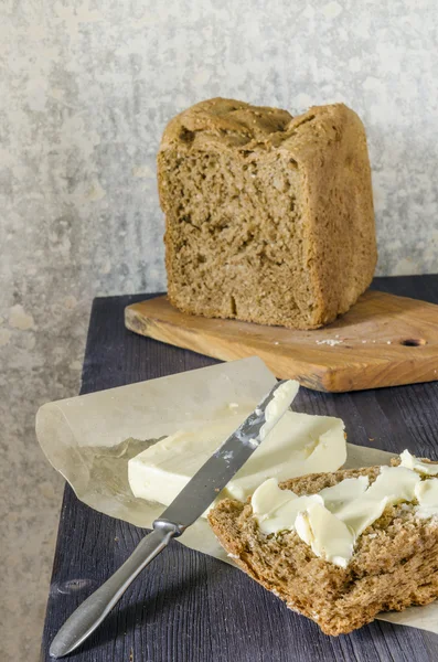 Homemade bread on cutting board with knife and butter — Stock Photo, Image