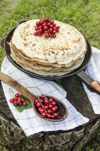 Pancakes with red currants on old pan — Stock Photo, Image