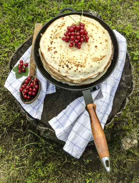 Pancakes with red currants on old pan and spoon — Stock Photo, Image