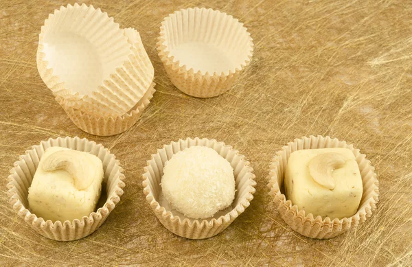 Witte chocolade zelfgemaakte truffels en papier verpakking op gouden achtergrond — Stockfoto