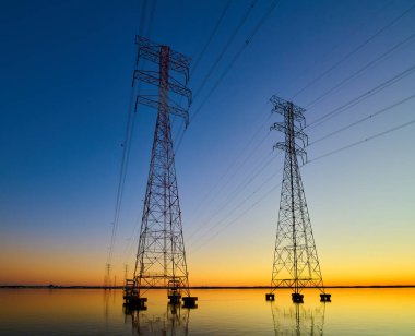 Atina AL yakınlarında Wheeler Gölü 'nden geçen yüksek voltaj iletim hatları. Gün batımında elektrik direkleri. Güç ve enerji.