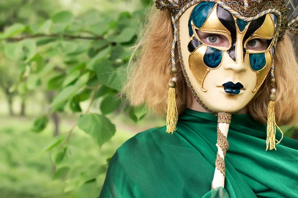 Beautiful woman in carnival mask over foliage background — Stock Photo, Image