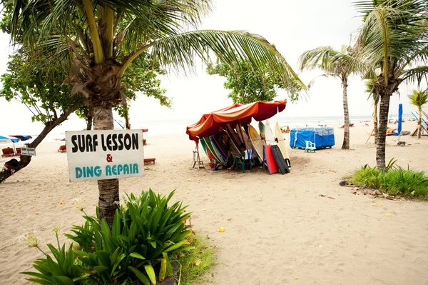 BALI- DECEMBER 28: Legian's beach. sign "Surf lesson & ding repa — Stock Photo, Image