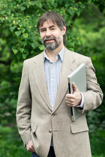 Retrato de homem de negócios de meia-idade feliz segurando notebook e s — Fotografia de Stock