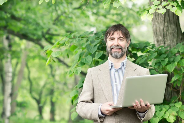 Портрет счастливого бизнесмена средних лет, держащего в руках ноутбук Лицензионные Стоковые Фото