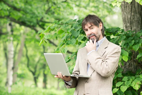 Портрет счастливого бизнесмена средних лет, держащего в руках ноутбук Стоковое Изображение