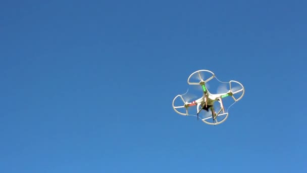 Quadrocopter flying overhead against a blue sky — Stock Video