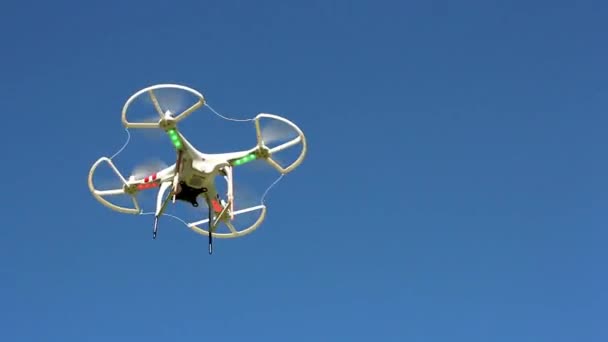 Quadrocopter flying overhead against a blue sky — Stock Video