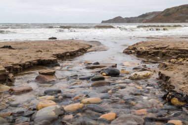 Runswick Körfezi 'ne çakıl taşlarının üzerinden geçen küçük bir gaga (dere).
