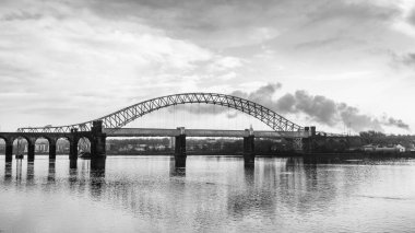 The iconic bridges linking Runcorn and Widness span the Mersey Estuary.  The Runcorn Railway Bridge sits closest to the camera and the Silver Jubilee Bridge is just behind it running in parallel. clipart