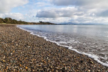 Dalgalar Kuzey Galler kıyısındaki Llanbedrog plajında, Snowdonia tepeleri tarafından destekleniyor.