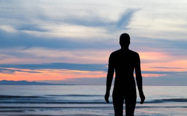 Eylül 2021 'de gün batımında Crosby sahilindeki başka bir yerde Demir Adam heykelinin silueti..