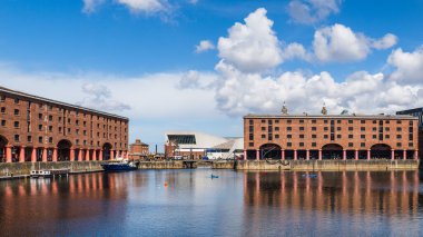 Dünyaca ünlü Liverpool siluetinin önündeki Albert Rıhtımı 'nda çok görüntülü bir kano manzarası. Eski depoların tepesinde Kraliyet Karaciğer Binası 'nda oturan iki karaciğer kuşu var..