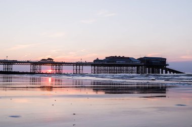 Kuzey Norfolk sahilindeki Cromer İskelesi 'nin arkasında gün batımı Haziran 2021' de doğu sahilinden alçak gelgitte yakalandı..