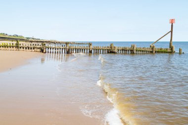 Kuzey Norfolk sahilindeki Cart Gap 'te dalgalar kıyıya vuruyor..